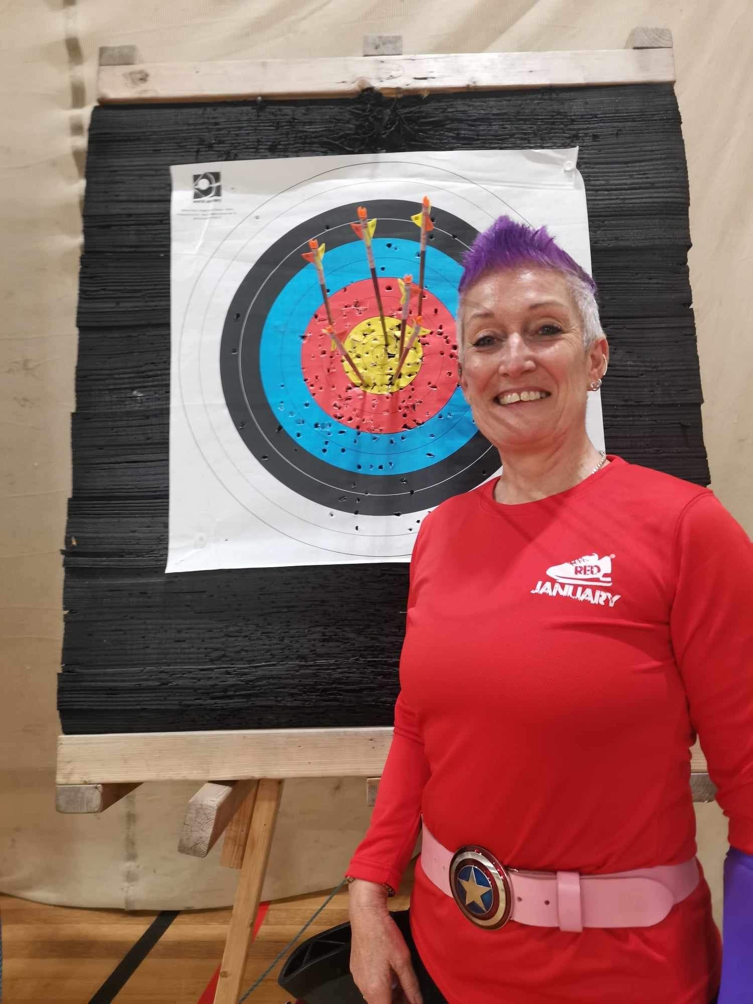 Mandie Elson wearing a Red January t-shirt, standing in front of an archery target