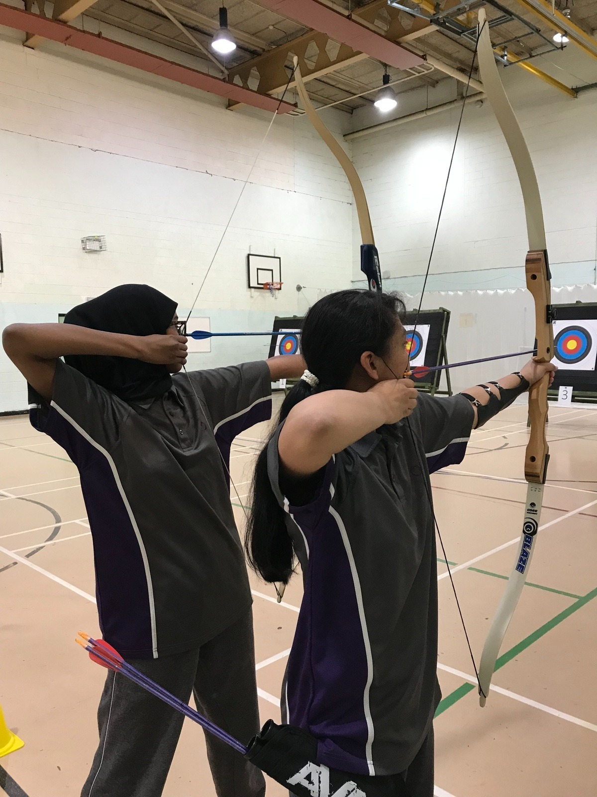 Two students doing archery in a secondary school