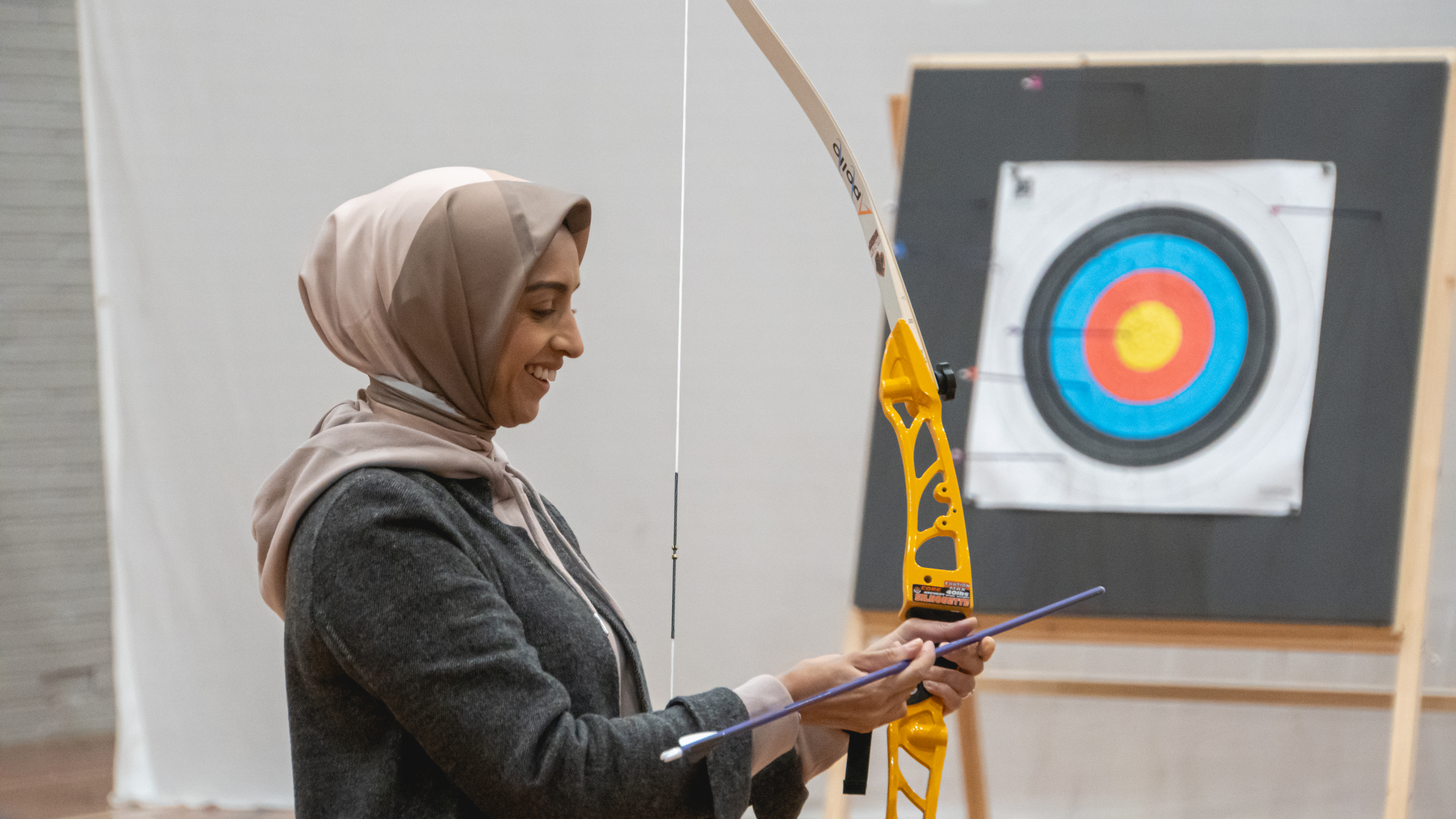 A woman nocks an arrow while smiling